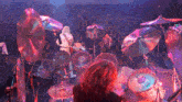 a man playing drums in front of a crowd with purple lights