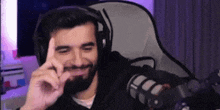 a man with a beard wearing headphones is sitting in front of a microphone and making a funny face .
