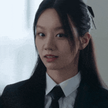 a woman wearing a suit and tie looks at the camera