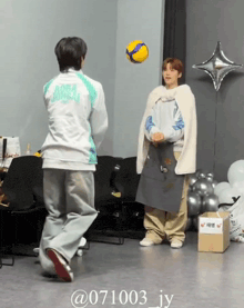 a man in a white jacket with the word aoba on the back is playing with a yellow ball