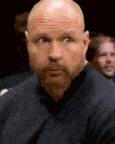 a bald man with a beard is making a funny face .