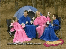 a family is sitting in front of a tent with blankets on