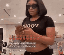 a woman wearing sunglasses and a black t-shirt is holding a cell phone .