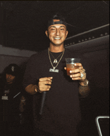 a man wearing a black shirt that says 2killer is holding a drink