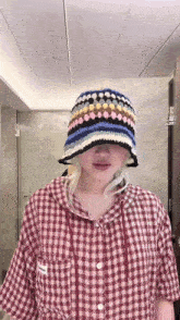 a woman wearing a red plaid shirt and a crocheted hat
