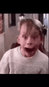 a young boy is making a funny face while wearing a white hat .
