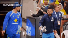 a man in a blue shirt is walking with a bat in his hand .