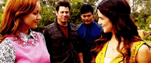 a group of people are standing next to each other in a park talking to each other .
