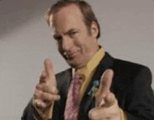 a man in a suit and tie is giving a thumbs up sign .