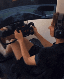 a man wearing headphones is playing a video game while holding a steering wheel