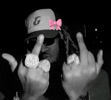 a man wearing a hat with the letter g on it gives the middle finger