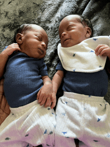 two babies wearing bibs are laying on a blanket