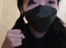 a woman wearing a black face mask holds her fist up in the air