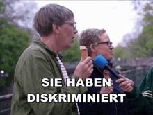 a man eating an ice cream cone next to a man holding a microphone with the words sie haben diskriminiert above him