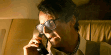 a man wearing glasses talks on a phone