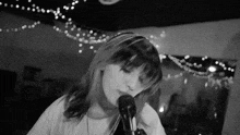 a black and white photo of a girl singing into a microphone .