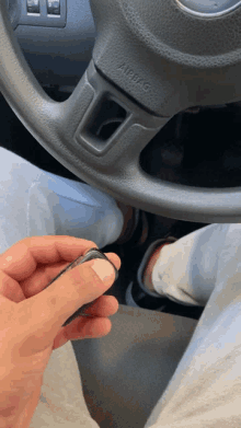 a person is holding a car key in front of a steering wheel that says airbag