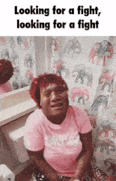 a woman in a pink shirt is sitting on a toilet with elephants on the shower curtain
