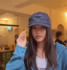 a girl wearing a blue hat that says khakis supplies 20
