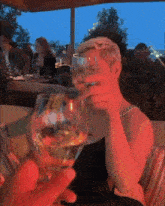 a woman is drinking a glass of wine while sitting at a table