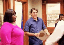 a woman in a pink shirt is standing next to a man in a blue shirt holding a piece of paper .