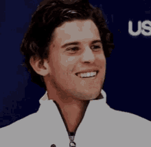 a close up of a man 's face smiling while wearing a white jacket .