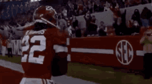 a football player with the number 22 on his jersey is running with a ball on a field .