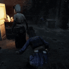 a man in a blue shirt is kneeling down in front of a fire
