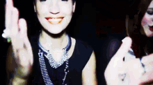 a woman in a black dress is smiling and giving a middle finger