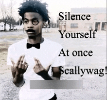 a man wearing a bow tie and glasses is standing in front of a building and giving the middle finger .