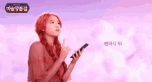 a woman with red hair is holding a cell phone in front of a purple sky