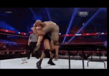two wrestlers are wrestling in a ring with a referee and a sign that says ' smackdown live '