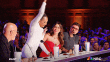 a group of people sitting at a table with a cup that says ' nbc ' on it