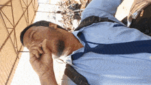 a man wearing a blue shirt and tie covering his face