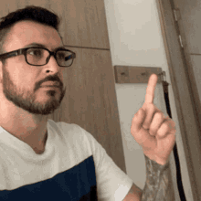a man with glasses and a beard points up