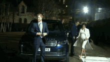 a man in a suit and tie is standing next to a pregnant woman in a white coat ..