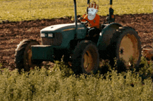 a man in a crown is driving a john deere tractor in a field