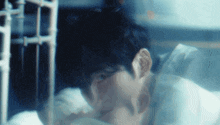 a blurry picture of a man laying on a bed with his head on his hand