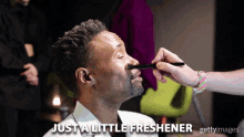 a man getting a little freshener applied to his nose