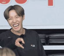 a man wearing a black fila shirt is laughing and pointing