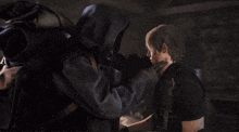 a man in a black jacket is standing next to another man in a black shirt