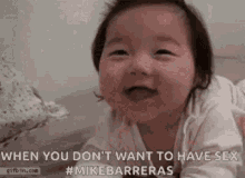 a baby is smiling while laying on its stomach on the floor .