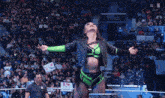 a woman in a green and black outfit stands in front of a crowd holding a sign that says raw