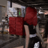 a woman with red hair is standing in front of a stack of red crates