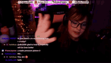 a woman wearing glasses and a seat headset is talking on a twitch stream