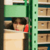 a man is peeking out from behind a shelf in a warehouse