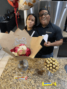 a man and a woman standing next to a bouquet of flowers and a happy anniversary sign