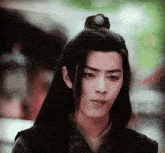 a young man with a bun on his head looks to the side