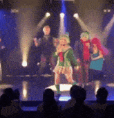 a group of people are dancing on a stage in front of an audience