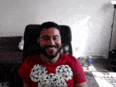 a man with a beard wears a red shirt with a mickey mouse on it